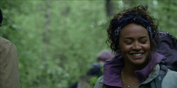 Movie still from “Blair Witch” (2016), directed by Adam Wingard – A woman smiles while standing in the woods; Close Up shot, Over the shoulder angle