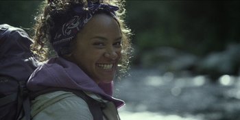 Movie still from “Blair Witch” (2016), directed by Adam Wingard – A woman smiling and wearing a purple scarf; Close Up shot, Over the shoulder angle