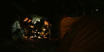 Movie still from “Blair Witch” (2016), directed by Adam Wingard – A group of people sitting around a fire at night; Wide shot, High angle
