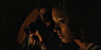 Movie still from “Blair Witch” (2016), directed by Adam Wingard – A woman is looking at the camera while a man takes a picture; Close Up shot, Over the shoulder angle