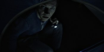 Movie still from “Blair Witch” (2016), directed by Adam Wingard – A man holding a flashlight in the dark; Close Up shot, Overhead angle