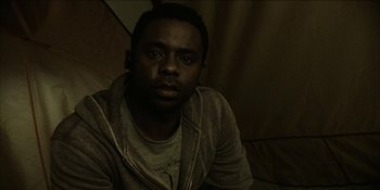 Movie still from “Blair Witch” (2016), directed by Adam Wingard – A man sitting on a couch in a dark room; Close Up shot, Low angle