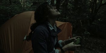 Movie still from “Blair Witch” (2016), directed by Adam Wingard – A woman sitting on a chair in the woods; Medium shot, Low angle