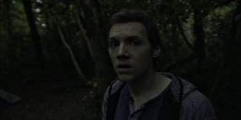 Movie still from “Blair Witch” (2016), directed by Adam Wingard – A young man standing next to a forest; Close Up shot, High angle