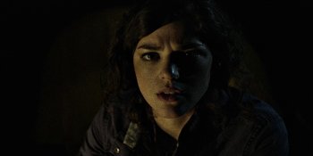 Movie still from “Blair Witch” (2016), directed by Adam Wingard – A young woman with dark curly hair stares into the camera; Close Up shot, Low angle
