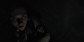 Movie still from “Blair Witch” (2016), directed by Adam Wingard – A man in the dark looking up at the camera; Close Up shot, Overhead angle