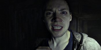 Movie still from “Blair Witch” (2016), directed by Adam Wingard – A young man with a bruised face is in the dark; Close Up shot, Low angle