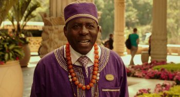 Movie still from “Blended” (2014), directed by Frank Coraci – A man in a purple hat and a necklace of orange beads; Close Up shot, Over the shoulder angle