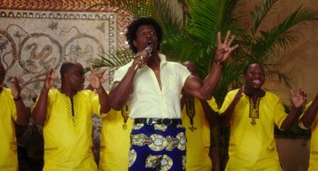 Movie still from “Blended” (2014), directed by Frank Coraci – A man singing into a microphone in front of a group of people; Medium shot, Low angle