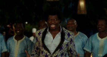 Movie still from “Blended” (2014), directed by Frank Coraci – A man in a colorful jacket is smiling; Medium shot, Over the shoulder angle