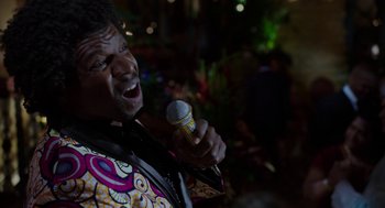 Movie still from “Blended” (2014), directed by Frank Coraci – A man is singing into a microphone in front of a crowd; Close Up shot, Over the shoulder angle