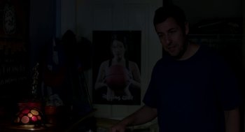Movie still from “Blended” (2014), directed by Frank Coraci – A man standing in front of a poster of a woman; Medium shot, Over the shoulder angle