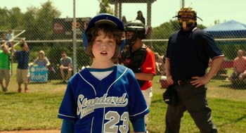 Movie still from “Blended” (2014), directed by Frank Coraci – A young baseball player wearing a blue uniform; Medium shot, Over the shoulder angle