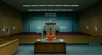 Movie still from “Blindspotting” (2018), directed by Carlos López Estrada – A man sitting at a desk in a courtroom; Extreme Wide shot, High angle