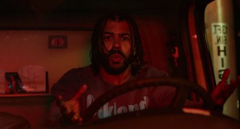 Movie still from “Blindspotting” (2018), directed by Carlos López Estrada – A man sitting in the driver's seat of a car; Medium shot, Low angle
