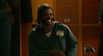 Movie still from “Blindspotting” (2018), directed by Carlos López Estrada – A man with dreadlocks is smiling for the camera; Close Up shot, Over the shoulder angle