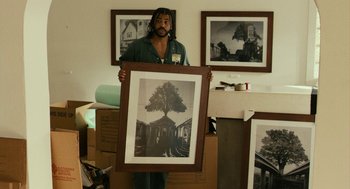 Movie still from “Blindspotting” (2018), directed by Carlos López Estrada – A man holding up a picture of a tree; Medium shot, Low angle