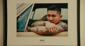 Movie still from “Blindspotting” (2018), directed by Carlos López Estrada – A man sitting in the back seat of a car with lots of tattoos on his arms; Close Up shot, Overhead angle