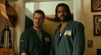 Movie still from “Blindspotting” (2018), directed by Carlos López Estrada – A couple of men standing next to each other; Medium shot, Low angle