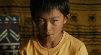 Movie still from “Blindspotting” (2018), directed by Carlos López Estrada – A young boy is holding a straw up to his mouth; Close Up shot, High angle