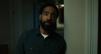 Movie still from “Blindspotting” (2018), directed by Carlos López Estrada – A man with a beard is standing next to a wall; Close Up shot, Low angle