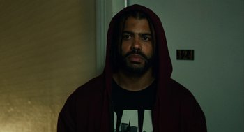 Movie still from “Blindspotting” (2018), directed by Carlos López Estrada – A man wearing a red hooded sweatshirt and a black shirt; Close Up shot, Low angle