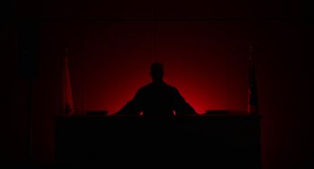 Movie still from “Blindspotting” (2018), directed by Carlos López Estrada – A man sitting in front of a red wall; Wide shot, Low angle