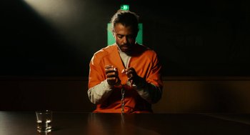 Movie still from “Blindspotting” (2018), directed by Carlos López Estrada – A man in an orange prison uniform holding a cell phone; Medium shot, Low angle