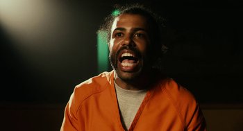 Movie still from “Blindspotting” (2018), directed by Carlos López Estrada – A man in an orange prison uniform is laughing; Close Up shot, Over the shoulder angle