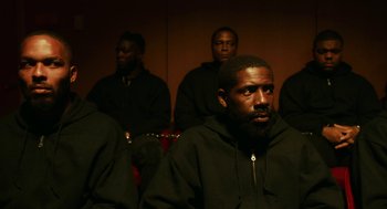 Movie still from “Blindspotting” (2018), directed by Carlos López Estrada – A group of men sitting in front of each other; Medium shot, High angle