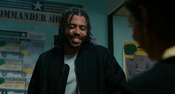 Movie still from “Blindspotting” (2018), directed by Carlos López Estrada – A man with long dreadlocks standing in front of a wall; Medium shot, Over the shoulder angle