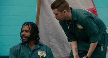 Movie still from “Blindspotting” (2018), directed by Carlos López Estrada – A man standing next to another man in a green shirt; Medium shot, Over the shoulder angle