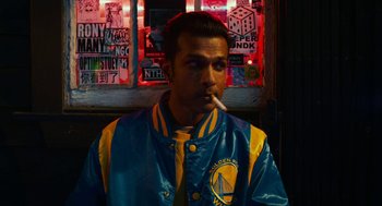 Movie still from “Blindspotting” (2018), directed by Carlos López Estrada – A man smoking a cigarette in front of a window; Medium shot, Low angle
