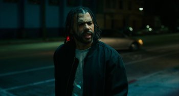Movie still from “Blindspotting” (2018), directed by Carlos López Estrada – A man with dreadlocks is standing on the street; Close Up shot, Over the shoulder angle
