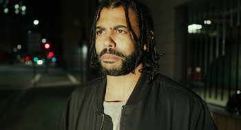 Movie still from “Blindspotting” (2018), directed by Carlos López Estrada – A man with long hair and a black jacket; Close Up shot, Low angle