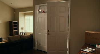 Movie still from “Blindspotting” (2018), directed by Carlos López Estrada – A white door in a room with a couch in the background; Wide shot, Low angle