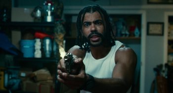 Movie still from “Blindspotting” (2018), directed by Carlos López Estrada – A man with dreadlocks is holding a gun in his hand; Medium shot, Low angle