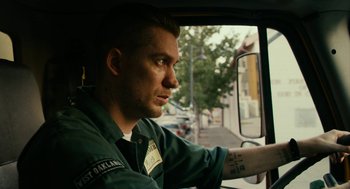 Movie still from “Blindspotting” (2018), directed by Carlos López Estrada – A man sitting in the drivers seat of a car; Close Up shot, Low angle