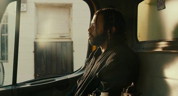 Movie still from “Blindspotting” (2018), directed by Carlos López Estrada – A man sitting in a car looking out the window; Medium shot, Low angle