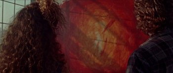 Movie still from “Bliss” (2019), directed by Joe Begos – A woman with curly hair is looking at a painting; Close Up shot, Overhead angle