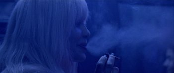Movie still from “Bliss” (2019), directed by Joe Begos – A woman is smoking a cigarette in the dark; Close Up shot, Over the shoulder angle