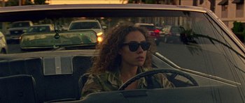 Movie still from “Bliss” (2019), directed by Joe Begos – A woman driving a car on a street; Medium shot, High angle