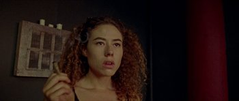 Movie still from “Bliss” (2019), directed by Joe Begos – A woman with curly red hair is smoking a cigarette; Close Up shot, Low angle