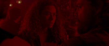 Movie still from “Bliss” (2019), directed by Joe Begos – A woman with long curly hair sitting in a room; Close Up shot, Over the shoulder angle