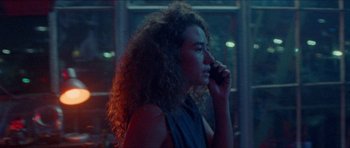 Movie still from “Bliss” (2019), directed by Joe Begos – A woman with curly hair talking on a cell phone; Close Up shot, Over the shoulder angle