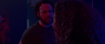 Movie still from “Bliss” (2019), directed by Joe Begos – A man stares into a mirror while standing in front of a woman; Close Up shot, Over the shoulder angle