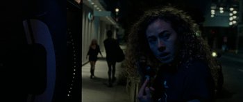 Movie still from “Bliss” (2019), directed by Joe Begos – A woman with curly hair is holding a cell phone in her hand; Close Up shot, Low angle
