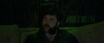 Movie still from “Bliss” (2019), directed by Joe Begos – A man with a long beard is sitting on a couch; Close Up shot, Low angle