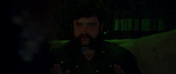 Movie still from “Bliss” (2019), directed by Joe Begos – A man with a goatee and a beard is in the dark; Close Up shot, High angle