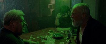 Movie still from “Bliss” (2019), directed by Joe Begos – Two men sitting at a wooden table playing poker; Medium shot, Over the shoulder angle